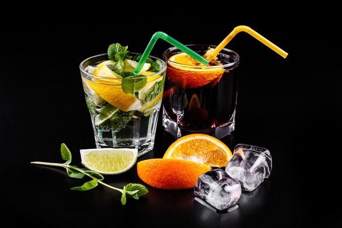 Two cocktails with citrus and mint on black background