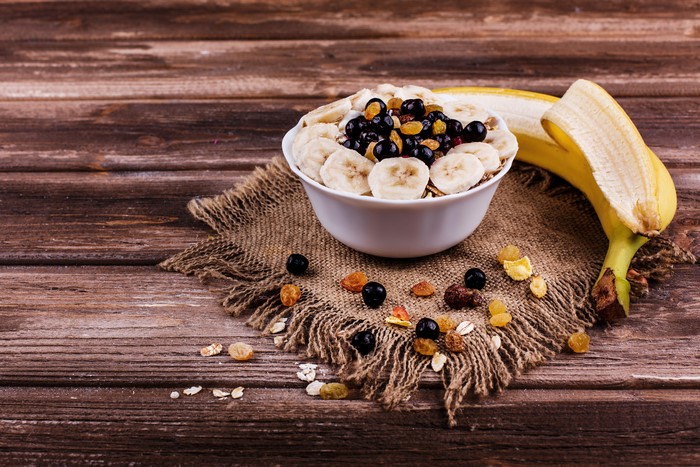 Bowl of Muesli with Bananas and Berries on Wood