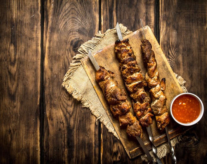 Shashlik on a wooden board with sauce