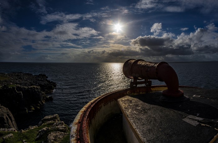 Rusty pipe on a cliff overlooking the sea at sunset