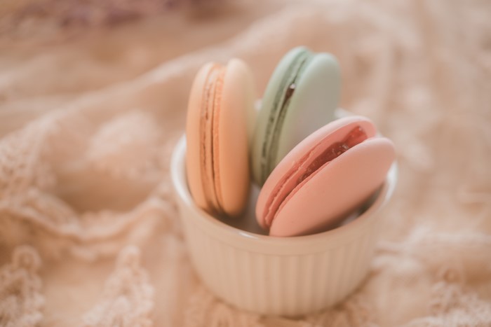 Three colorful macarons in a white bowl
