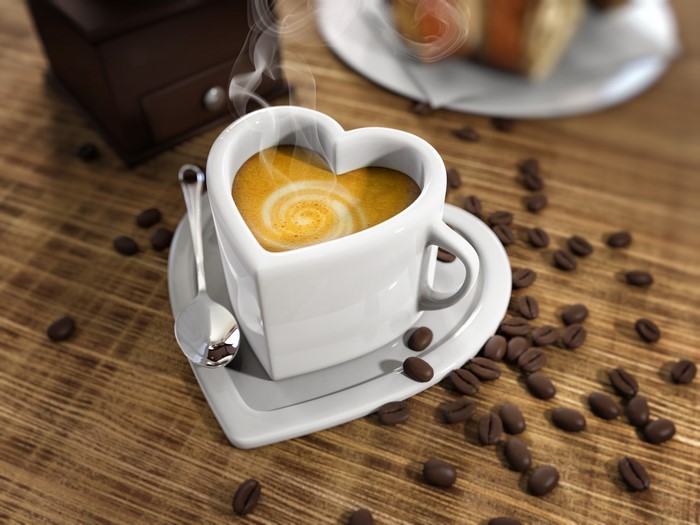 Heart-shaped coffee cup with latte art and coffee beans