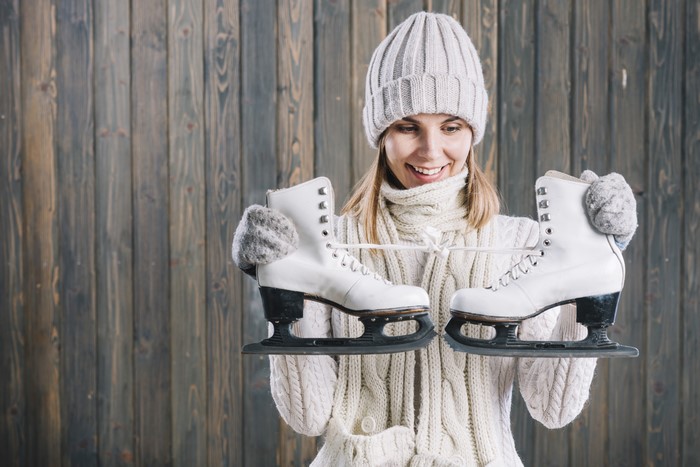 Woman in winter hat holding ice skates