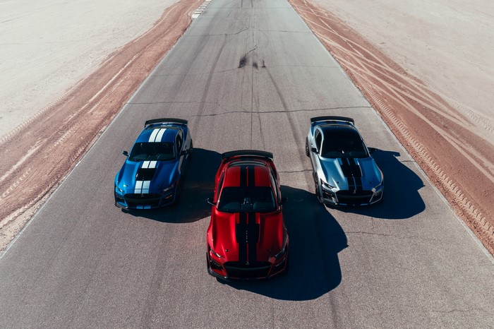 Three Ford Mustang Shelby GT500 cars on a racetrack