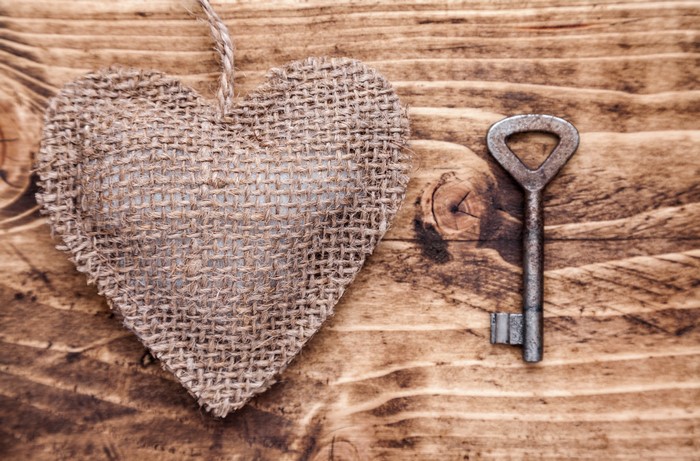 Burlap heart and antique key on wood
