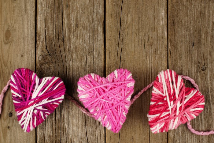 Three yarn hearts on wood planks