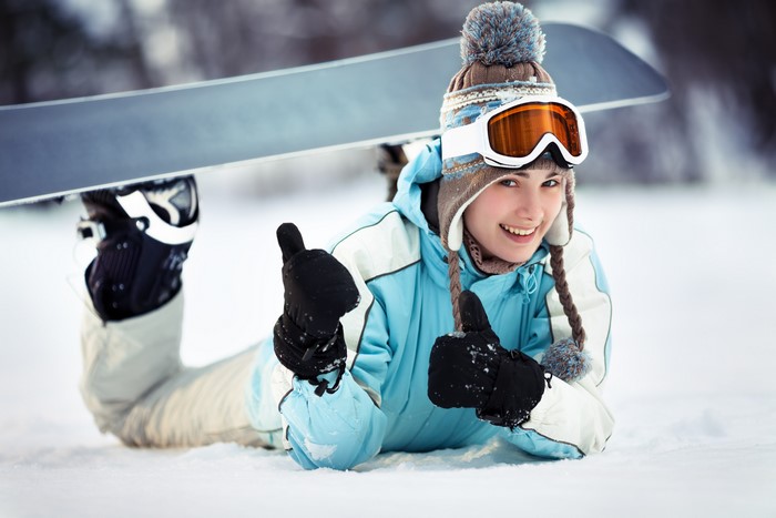 Girl in winter hat and goggles with snowboard