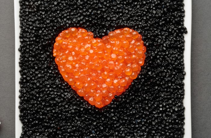 Heart shape made of salmon roe on black caviar