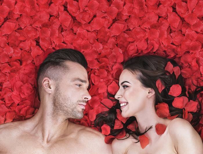 Couple lying on red rose petals