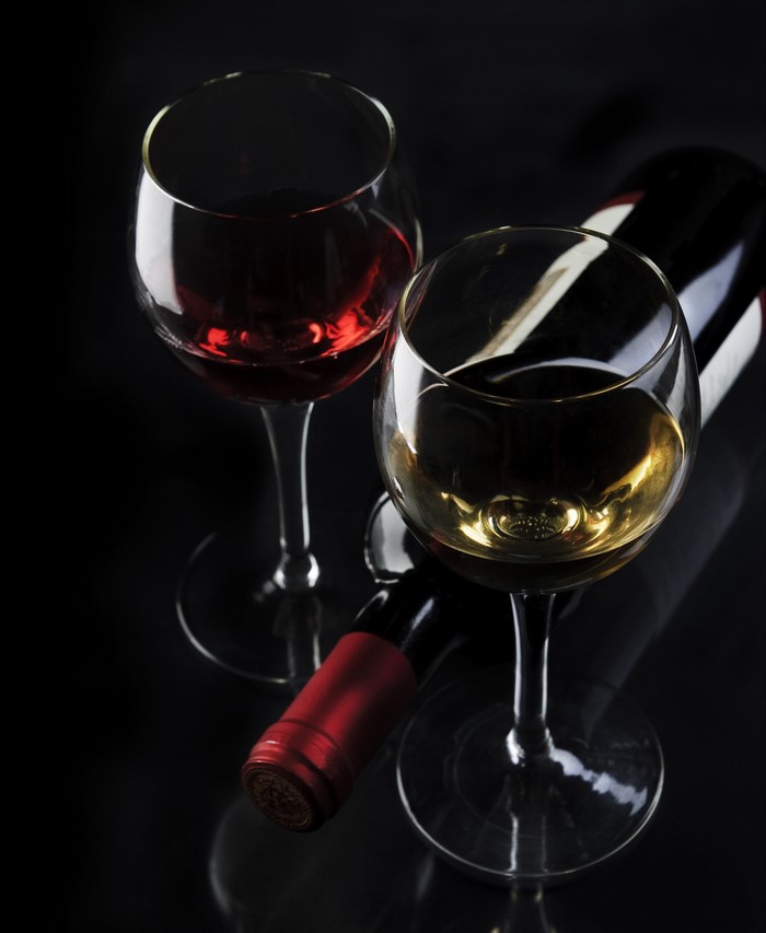 Red and white wine glasses with bottle on black background