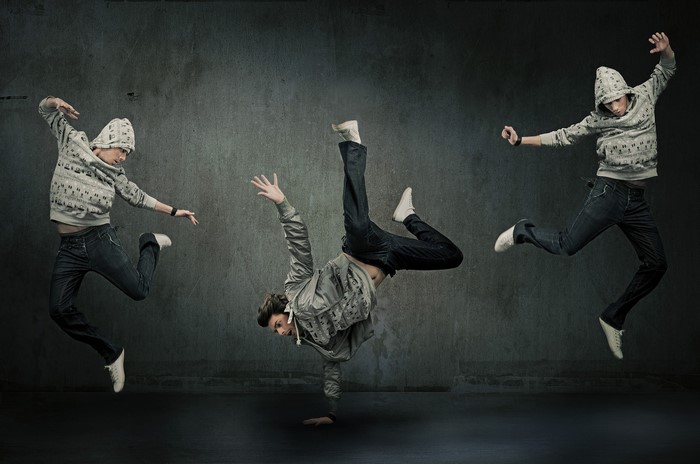 Three men dancing and jumping in front of a wall