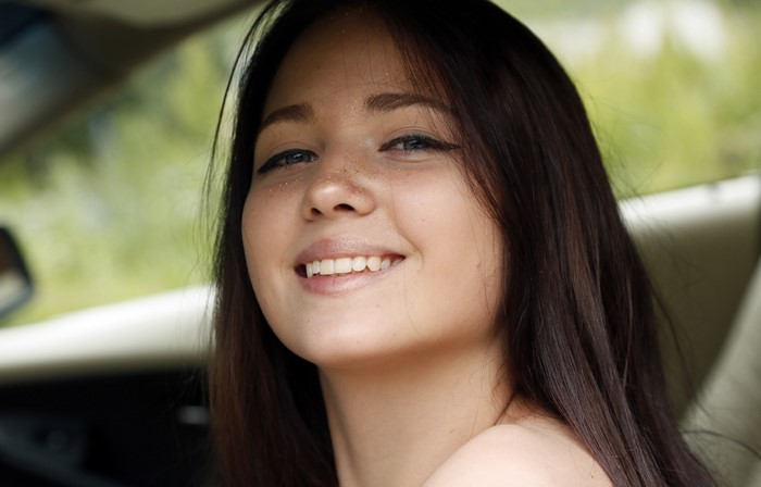 Young woman with freckles smiling in a car