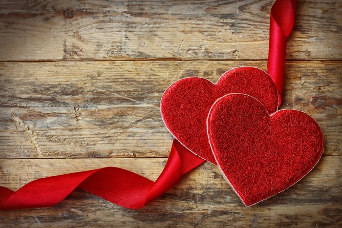 Two red hearts with red ribbon on wood planks