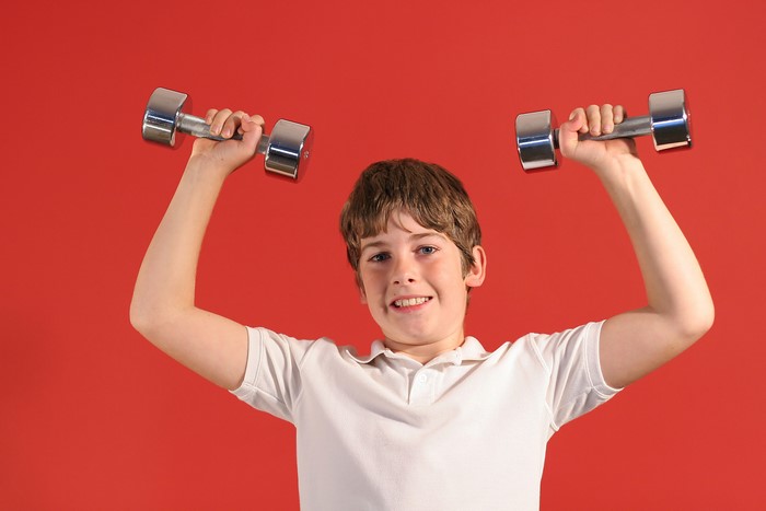 Boy holding dumbbells on red background