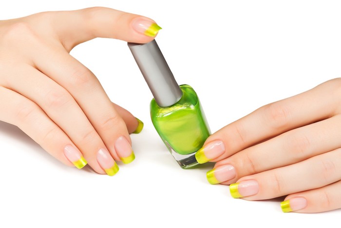 Hands with green French manicure holding nail polish bottle