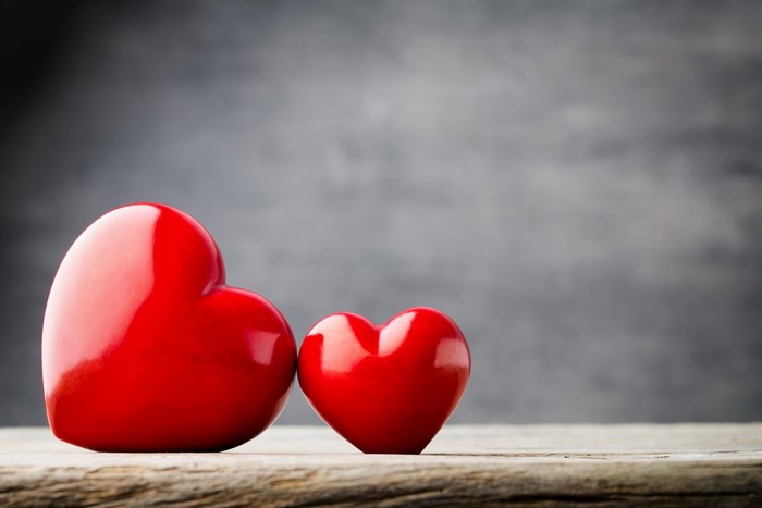 Two red hearts on a wooden surface