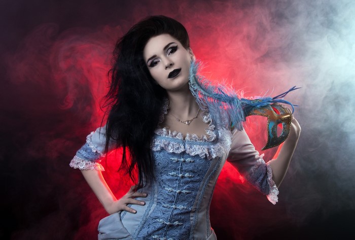 Woman in blue corset holding a masquerade mask