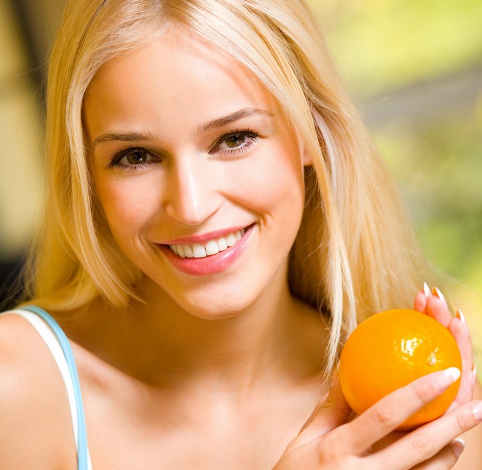 Blonde girl holding an orange