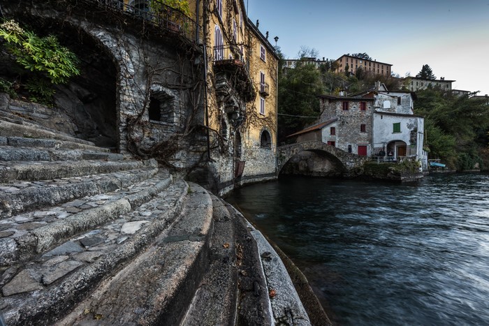 Stone stairs and buildings by a river in Nesso, Italy