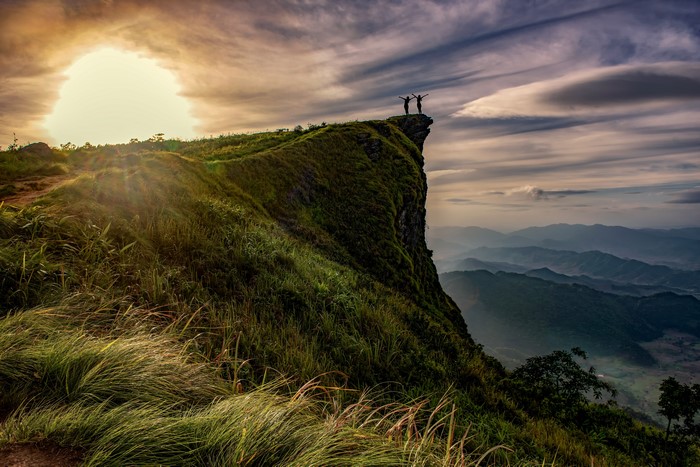 Two people on a cliff at sunset