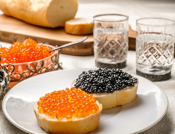 Caviar on bread with vodka and bread on a cutting board