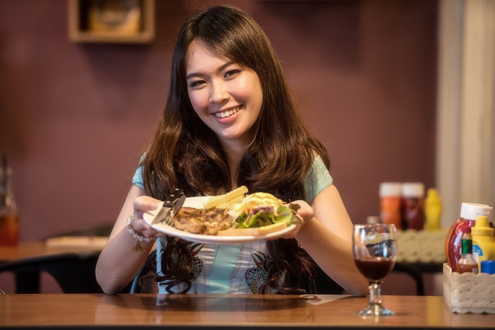 Asian woman smiling with steak and fries