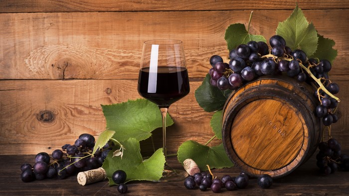 Wine glass, grapes, and barrel on wood