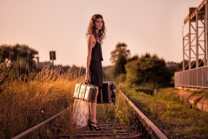 Woman with suitcases on railroad tracks