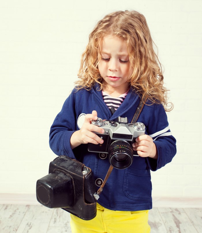 Young girl with curly hair holding a vintage camera