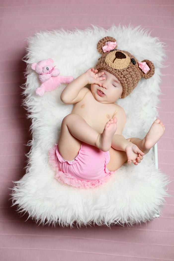 Baby wearing a teddy bear hat and pink bloomers