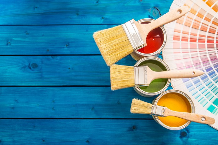 Three paint cans with brushes and color swatch