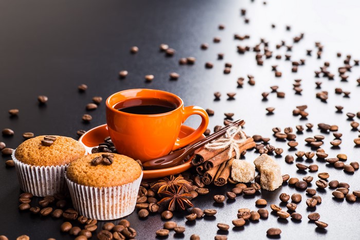 Coffee cup with muffins, cinnamon, and coffee beans