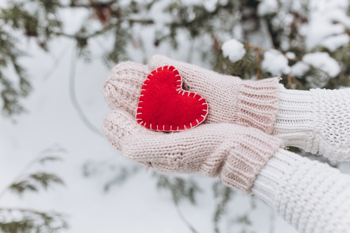 Hands in Mittens Holding a Red Heart in Snow