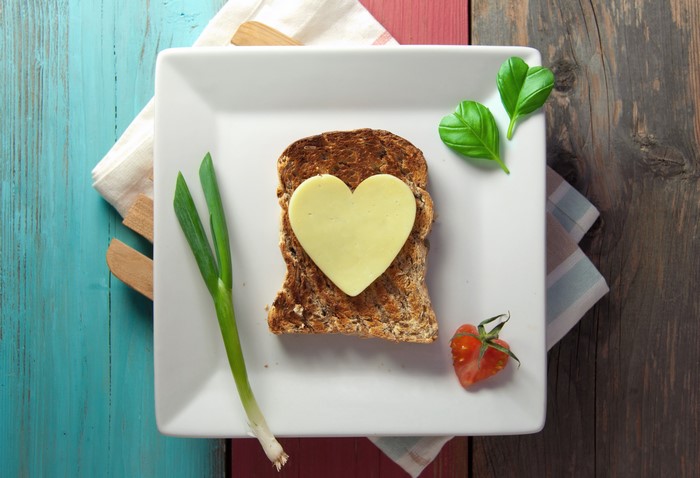 Heart-shaped cheese on toast with spring onion and tomato