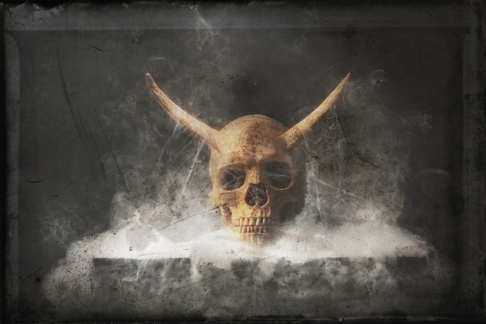 Skull with horns emerging from smoke