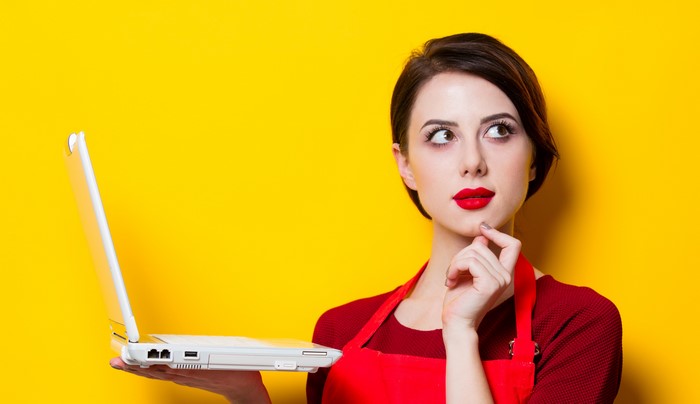 Woman in red apron holding a laptop