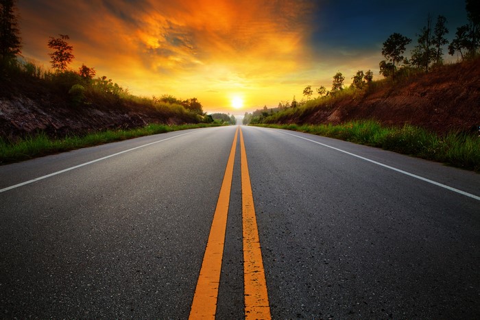 Asphalt road with double yellow lines at sunset