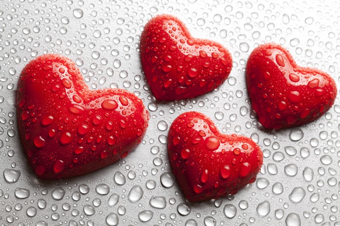 Four red hearts with water drops