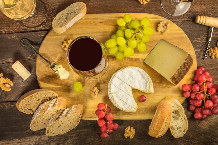 Wine, Cheese, Bread, Grapes, and Nuts on a Cutting Board