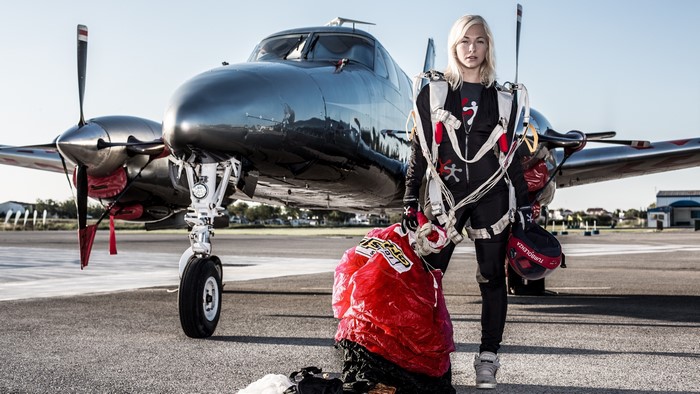 Woman in skydiving gear with airplane