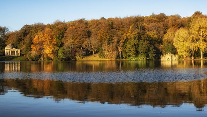 Autumn trees reflected in a lake with a classical temple