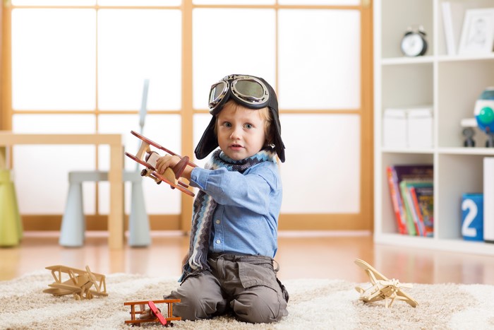 Boy in pilot costume playing with toy airplanes