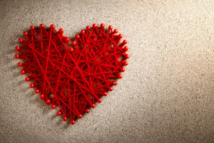 Red string heart on cork board