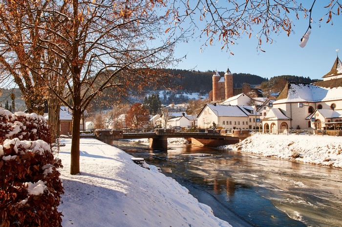 Winter scene in Murlenbach, Germany with river and snow-covered houses