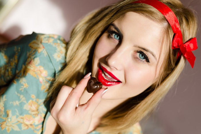 Woman with red lips holding heart-shaped chocolate