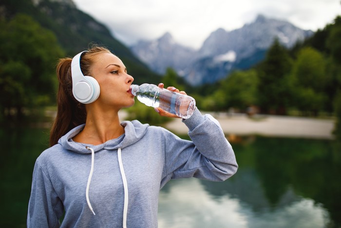Woman with headphones drinking water from bottle