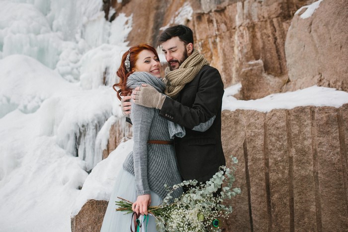Couple hugging in winter near icy waterfall