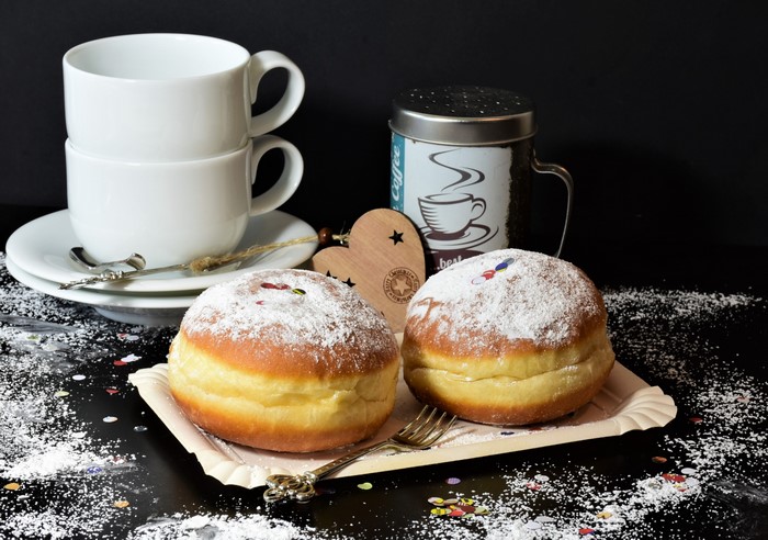 Two donuts with powdered sugar and coffee cups