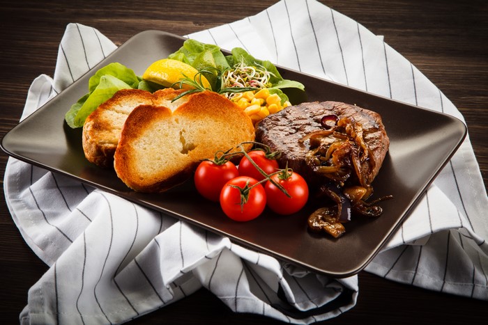 Steak with bread, tomatoes, and salad