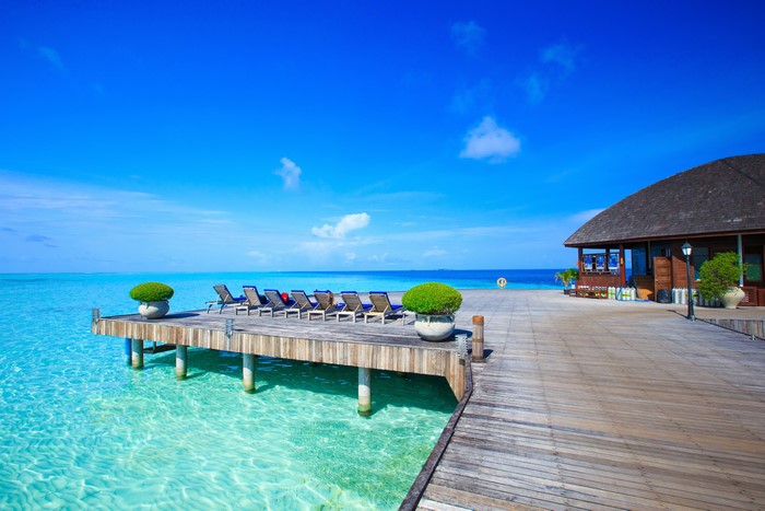 Maldives resort with wooden pier and lounge chairs